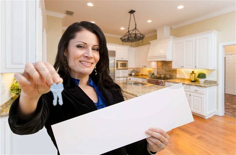 Pretty Hispanic Woman In Kitchen Holding House Keys and Blank White Sign, stock photo