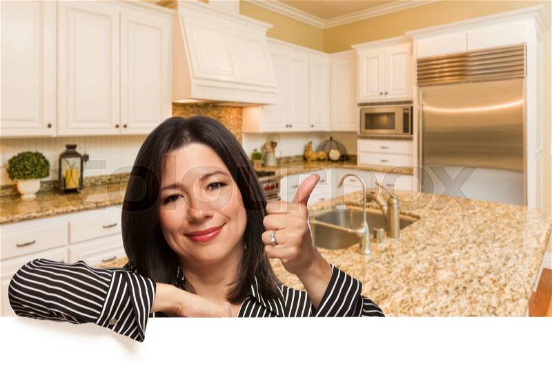 Hispanic Woman with Thumbs Up In Custom Kitchen Interior Leaning on White, stock photo