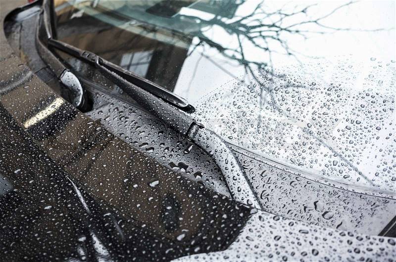 Black car hood fragment and windshield wipers with raindrops on it, closeup photo with selective focus and shallow DOF, stock photo