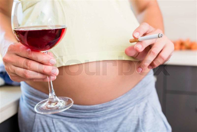 Woman is pregnant but drinks alcohol and smokes cigarettes, stock photo