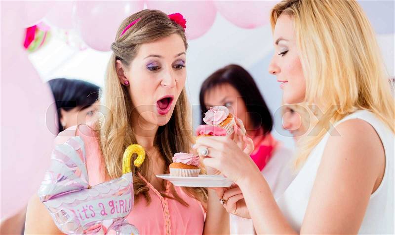 Expecting mother eating pink cupcake on baby shower party, stock photo