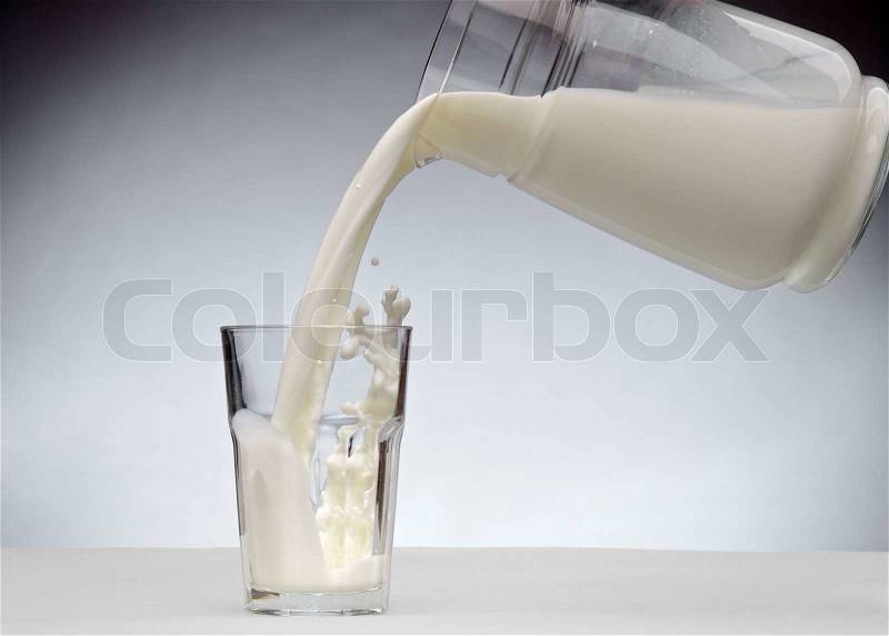 Pouring a glass of milk with splash from jug, stock photo