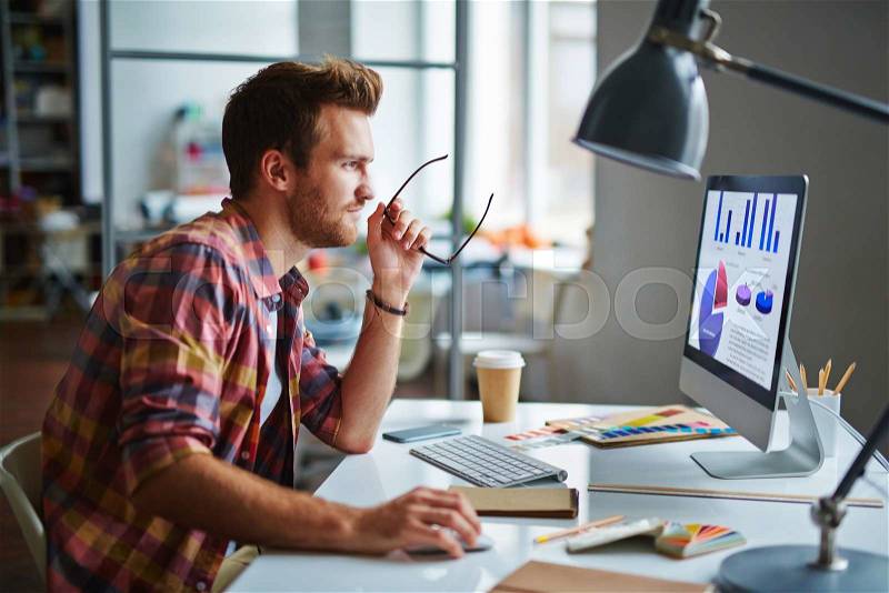 Man as a designer sitting at his table and working on computer, stock photo