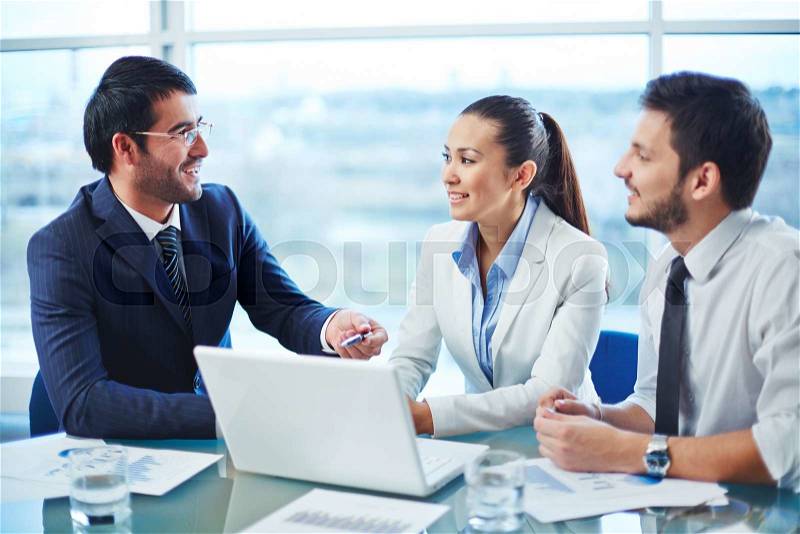 Business people sitting at the table and discussing project on laptop, stock photo