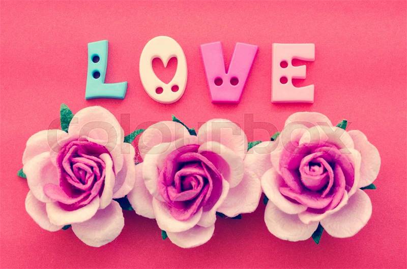 Vintage pink roses flower and love text on red background, stock photo