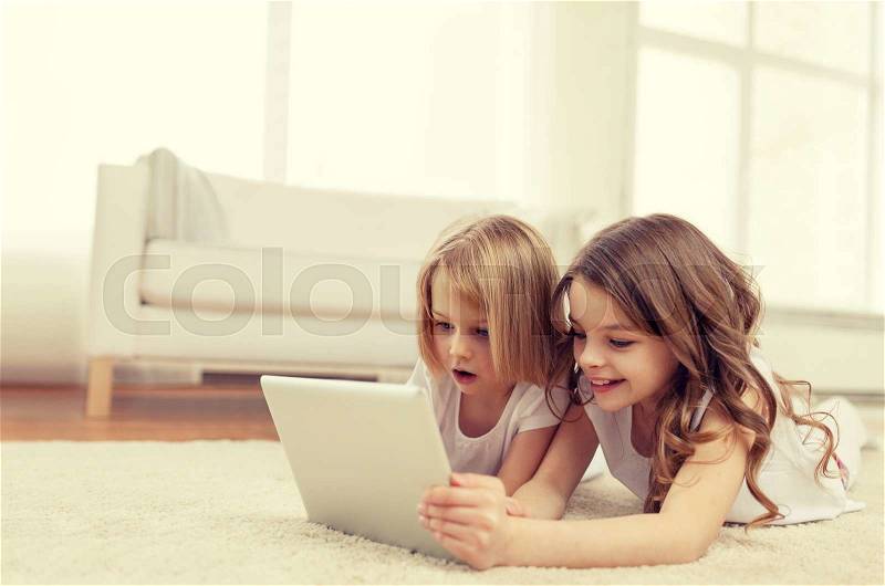 Children, technology and home concept - two little girls with tablet pc computer lying on floor at home, stock photo