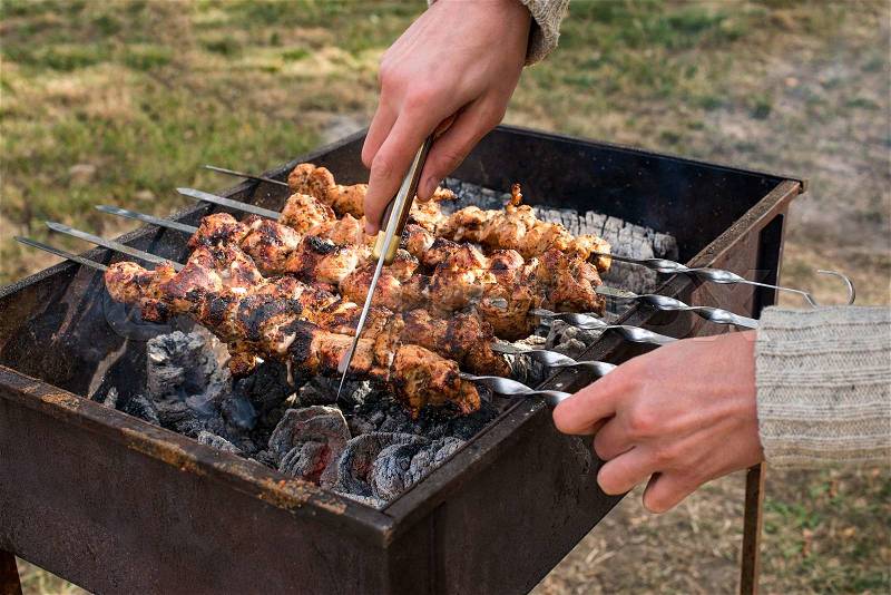 Man cooking, only hands, he is cutting meat or steak for a dish. Delicious grilled meat on grill. Barbecue weekend. Selective focus, stock photo