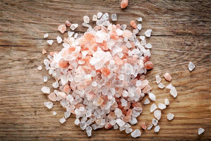 Heap of pink himalayan salt on wooden table, top view, stock photo