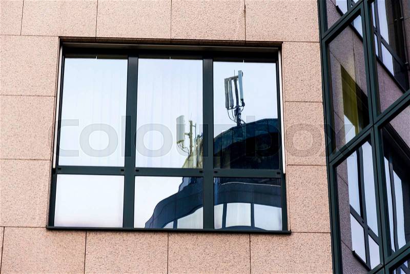 The mobile radio transmitter of a mobile operator\'s reflected in a window. mobile transmitters and electromagnetic pollution, stock photo