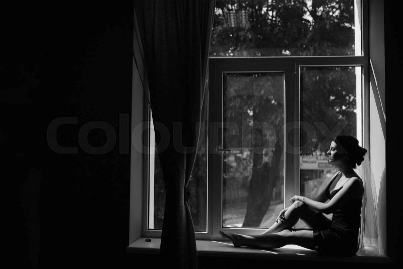 Bride in the morning sitting on the windowsill, stock photo