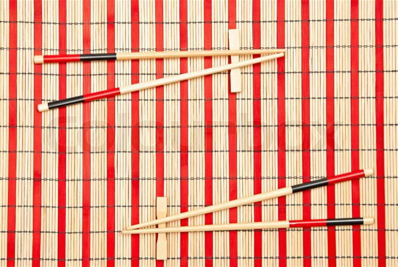 Red and black sticks for sushi on bamboo mat, stock photo