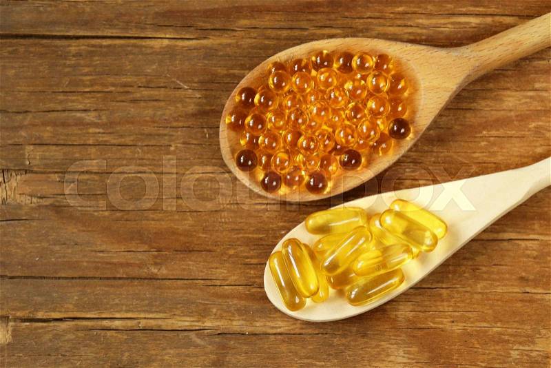 Food supplement of fish oil capsules in a wooden spoon - healthy food, stock photo