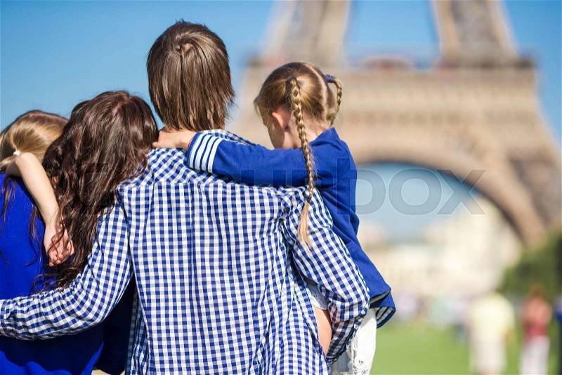 Happy family of four having fun together in Paris near the Eiffel tower, stock photo