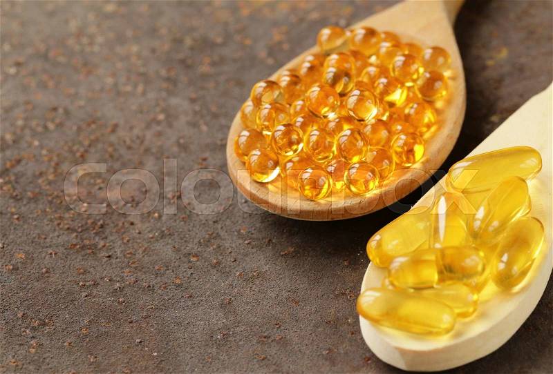 Food supplement of fish oil capsules in a wooden spoon - healthy food, stock photo