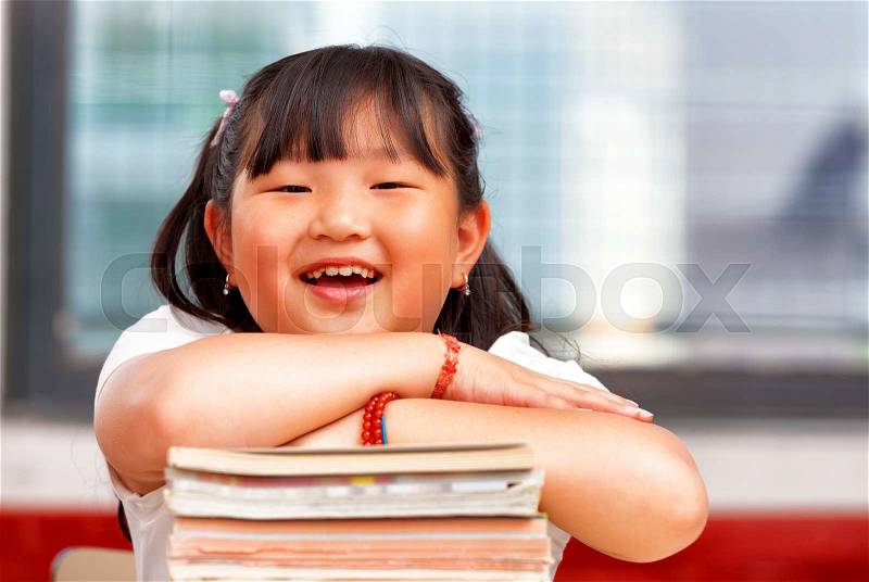 Happy chinese girl at primary school holding her books, stock photo