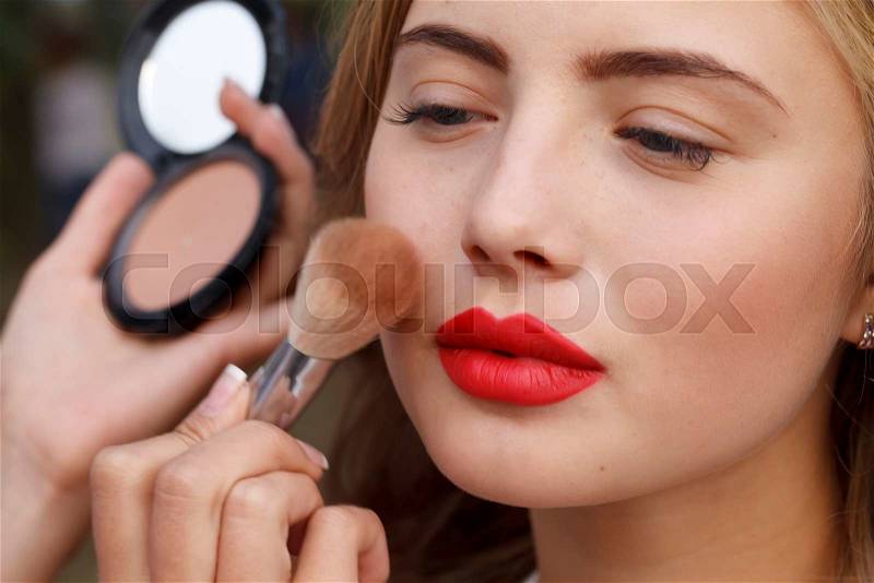 A makeup master paint a beautiful young girl closeup, stock photo