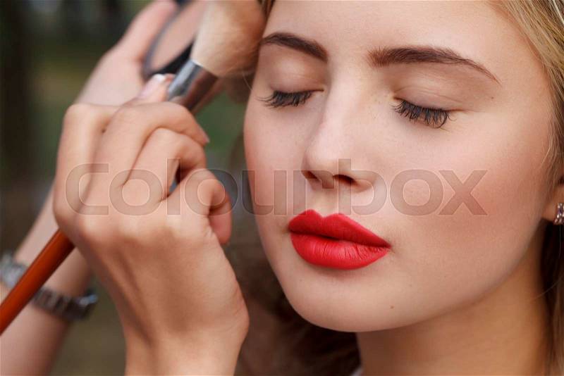 A makeup master paint a beautiful young girl closeup, stock photo
