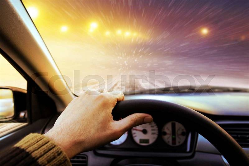 Driving on snow covered winter road with shining streetlights at night, stock photo