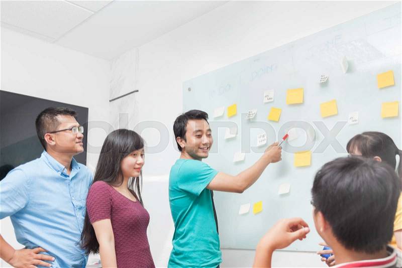 Asian business people team drawing on white wall whiteboard with sticky notes creative real office, stock photo
