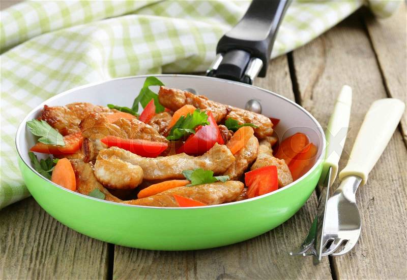 Fried chicken (turkey) fillets with vegetables in a pan, stock photo