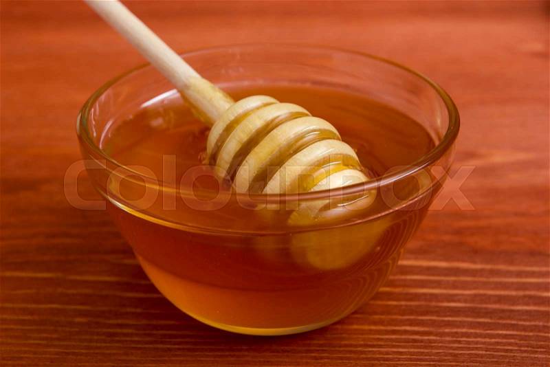 Wooden honey stick to extract honey from the container, stock photo