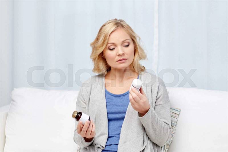 Medicine, health care and people concept - woman looking at jars with medicine at home or hospital office, stock photo