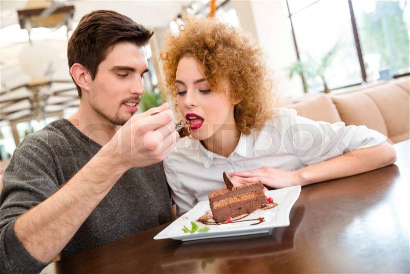 Portrait of a happy couple eating cake in restaurant, stock photo