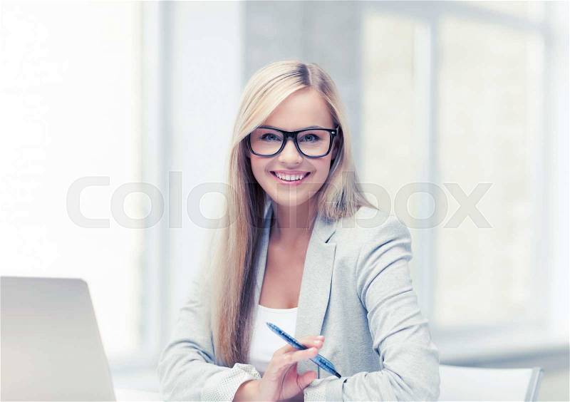 Indoor picture of smiling woman with laptop and pen, stock photo