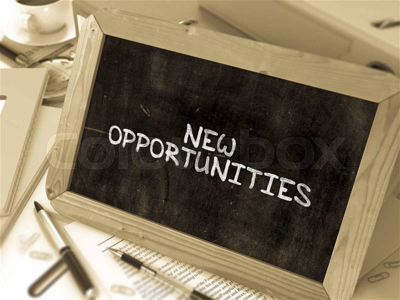 New Opportunities - Chalkboard with Hand Drawn Text, Stack of Office Folders, Stationery, Reports on Blurred Background. Toned Image, stock photo