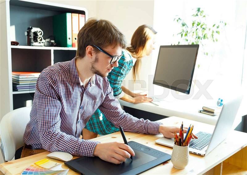 Young artist drawing something on graphic tablet at the home office, stock photo