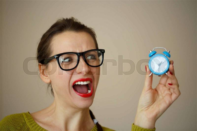 Little blue alarm clock in the hands of an emotional young woman, concept of saving time, stock photo