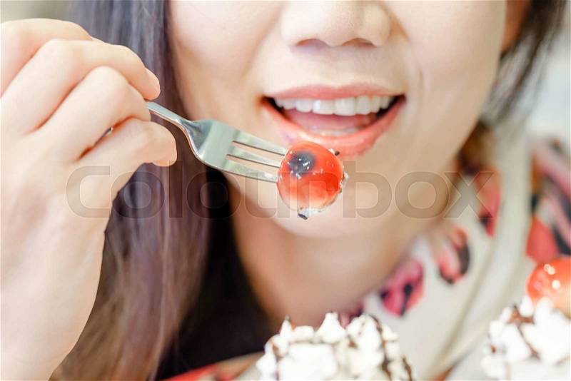 Women smiling and using fork eating cherry in cake, stock photo