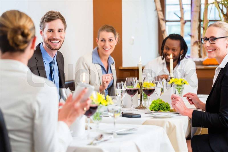 Team having business lunch in restaurant toasting with red wine to celebrate , stock photo