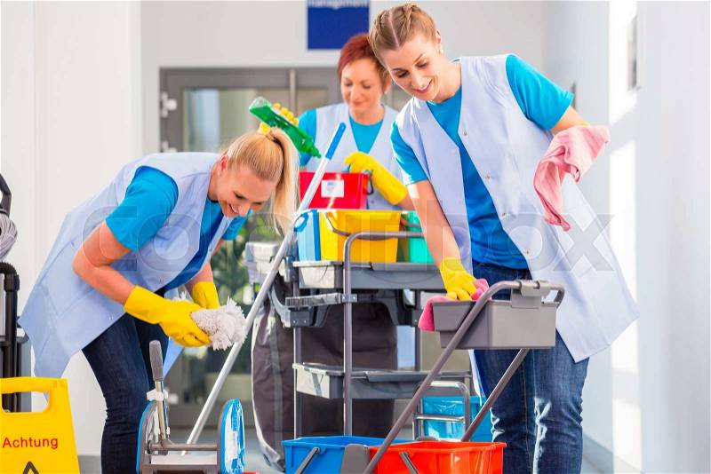 Commercial cleaners doing the job together, three women with trolley working , stock photo