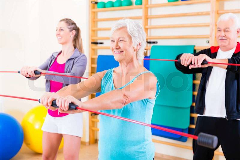 Group at fitness training with gymnastic bar, young and senior people exercising, stock photo