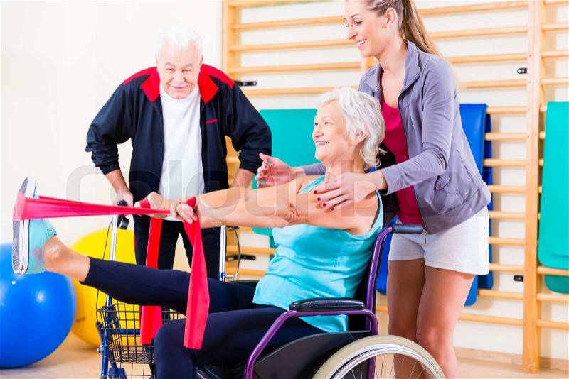 Seniors in physical rehabilitation therapy with trainer, stock photo