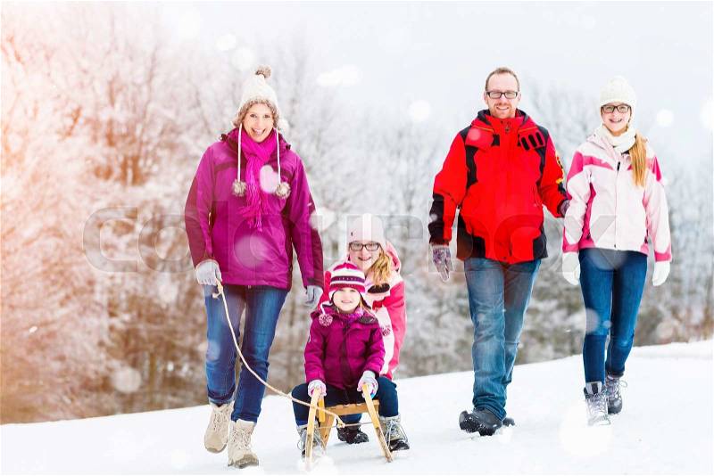 Family having winter walk in snow with sled, stock photo