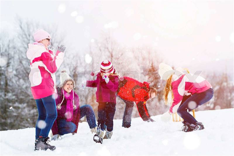 Family playing in snow having fight with snowballs, stock photo