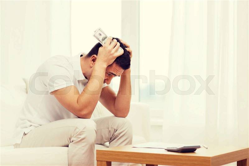 Business, savings, financial crisis and people concept - man with money and calculator at home, stock photo