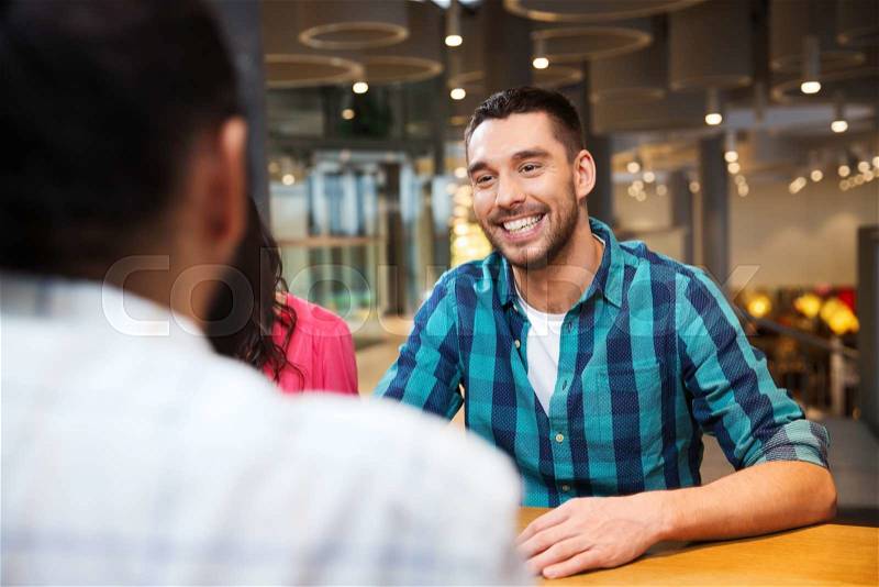 Leisure, communication and people concept - happy smiling man meeting with friends at restaurant, stock photo