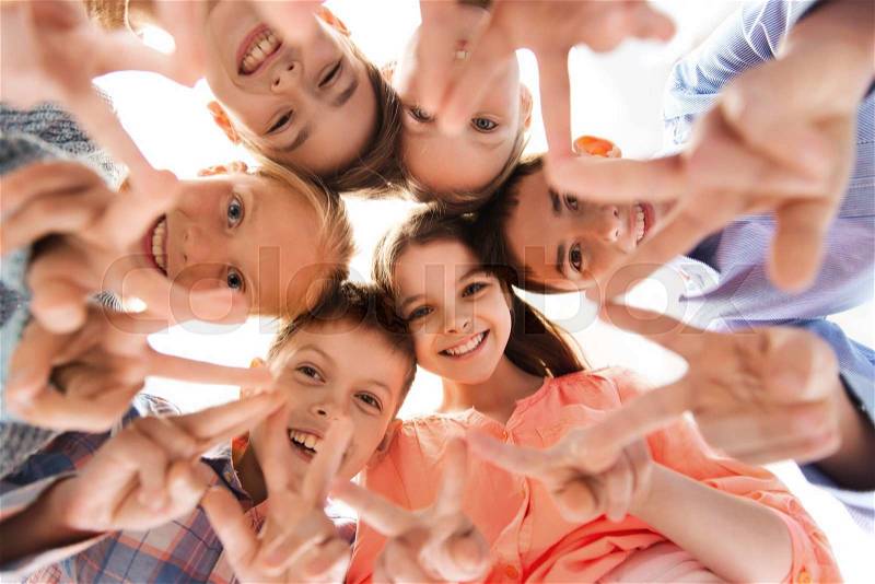 Childhood, fashion, friendship and people concept - happy smiling children showing peace hand sign and standing in circle, stock photo
