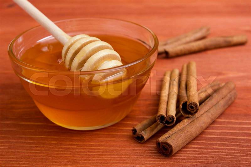 Wooden honey stick to extract honey from the container and cinnamon sticks, stock photo