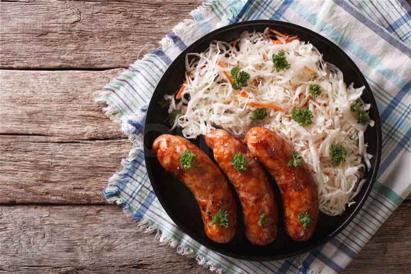 Grilled sausages and sauerkraut on a plate on a table close-up. horizontal top view , stock photo