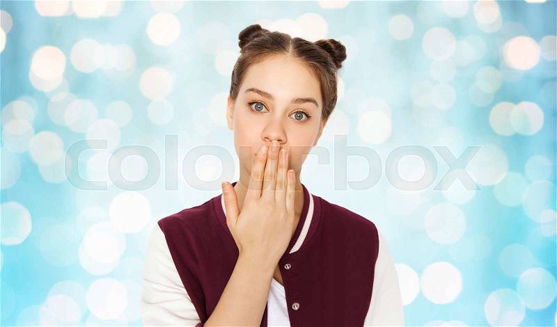 People, emotion, expression and teens concept - confused teenage girl covering her mouth by hand over blue holidays lights background, stock photo
