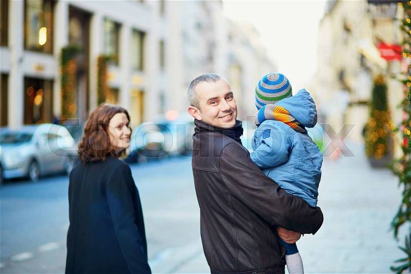 Happy family of three walking together on a street of Paris, stock photo