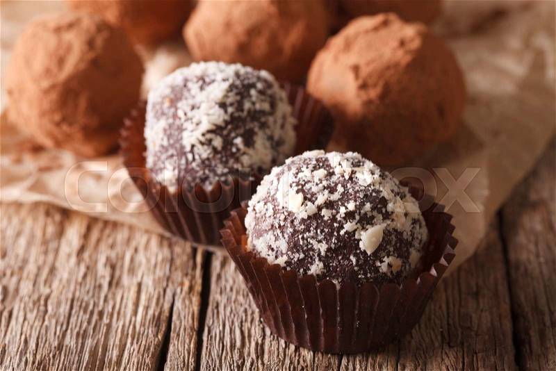 Chocolate truffles sprinkled with nuts on a wooden table macro. horizontal , stock photo