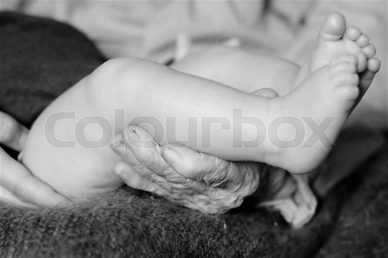 Black and white shot of hands of a grandmother holding little baby, stock photo