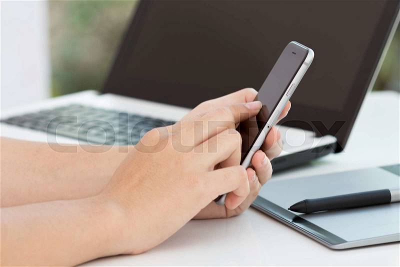 Hand touch on black phone on desk, stock photo