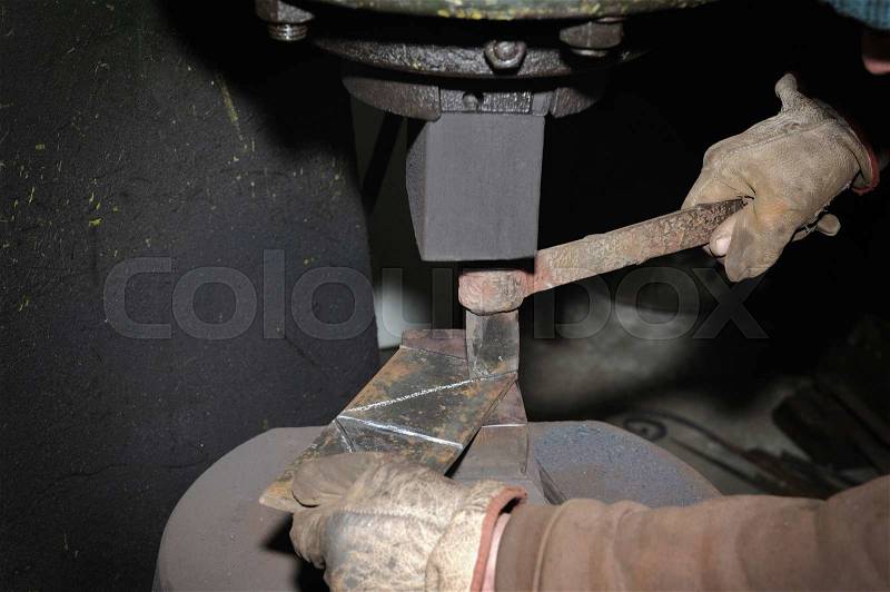 Blacksmith hammering hot iron automatic hammer, stock photo