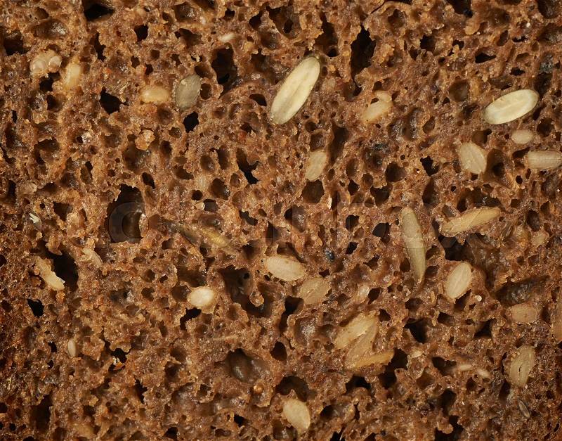 Black bread with seeds close-up fragment as a backdrop texture composition, stock photo
